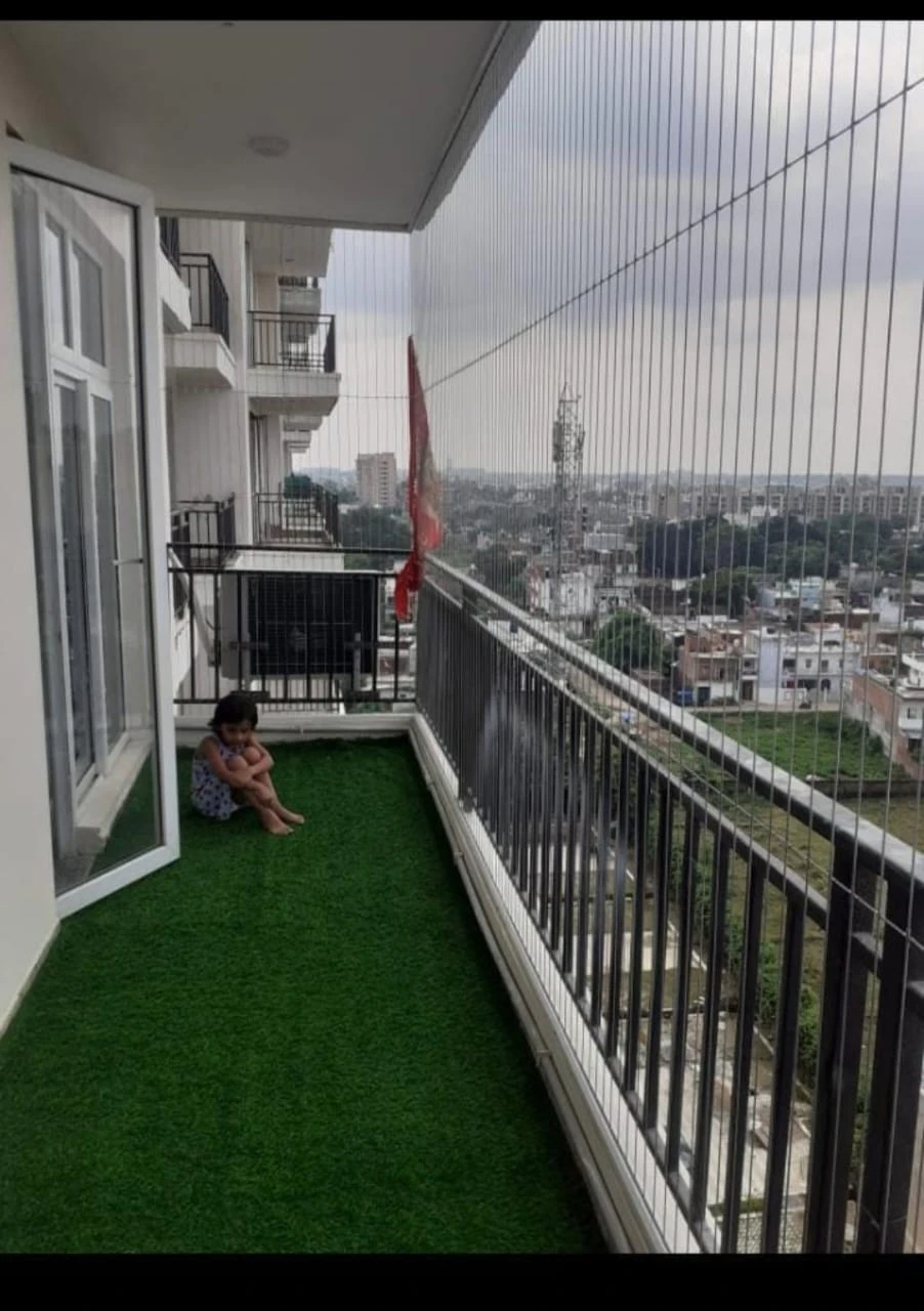 Child sitting safely on a Hyderabad balcony fitted with children safety invisible grills